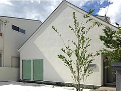急勾配の大屋根が印象的な外観。建物がシンプルなゆえに植栽の桂が映えます。